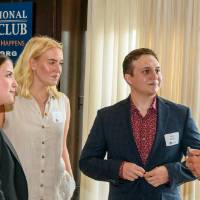 Group of 4 alumni stand in circle and talk at event